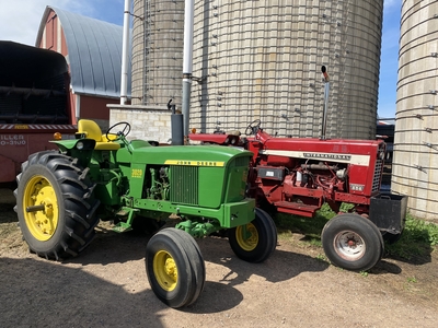 Tractors with a chopper wagon and blower in front of silos and barn in Bloomer, WI